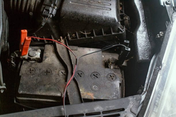Jump leads connected to a flat car battery under the bonnet