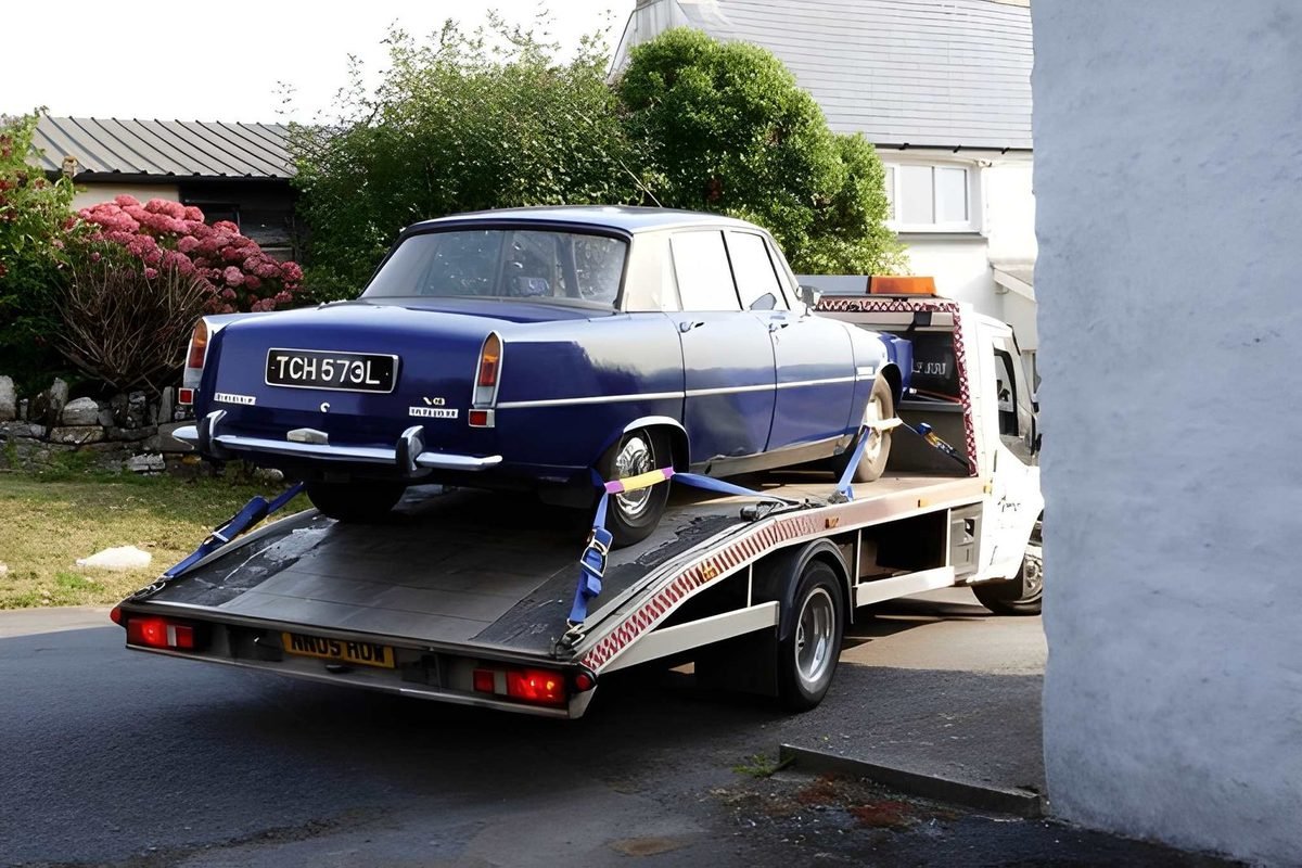 Classic blue saloon strapped down on a flatbed recovery truck